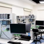 Laboratório de informática com estações de trabalho e equipamentos eletrônicos avançados para pesquisa e desenvolvimento.