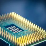 Imagem em close de um chip de computador com pinos dourados sobre fundo azul.