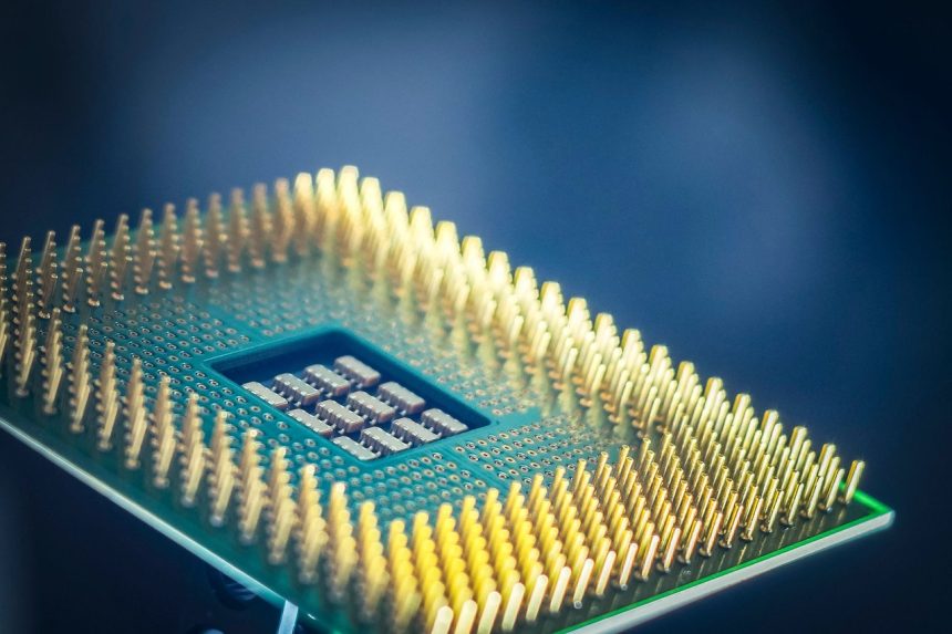 Imagem em close de um chip de computador com pinos dourados sobre fundo azul.