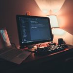 Escritório doméstico com dois monitores exibindo um ambiente de programação e desenvolvimento de software.